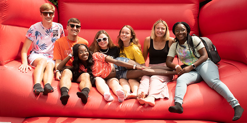 Illinois State University students posing on a Welcome Week's big red chair.
